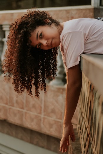 Photo of Girl Leaning Forward on Concrete Railing Posing