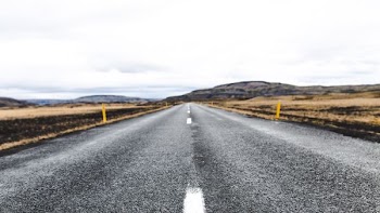 photo of grey and white asphalt road under white cloudy sky