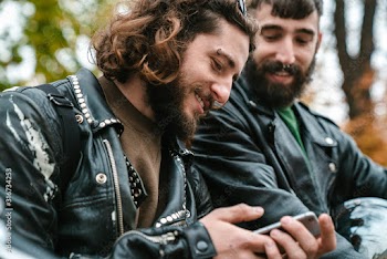 Photo of handsome joyful men smiling and using cellphone