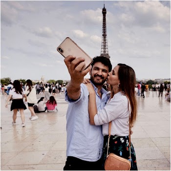 Photo of Hugging Couple Taking Selfie With a Crowd of People and The Eiffel Tower in the Background