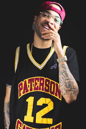 Photo of Laughing Man Wearing Black and Yellow Basketball Jersey Posing In Front of Black Background