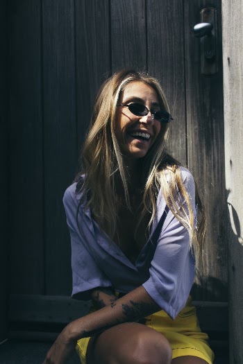 Photo of Laughing Woman Sitting in Front of  Wooden Door