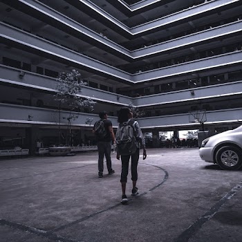 Photo of Man and Woman Walking in Campus