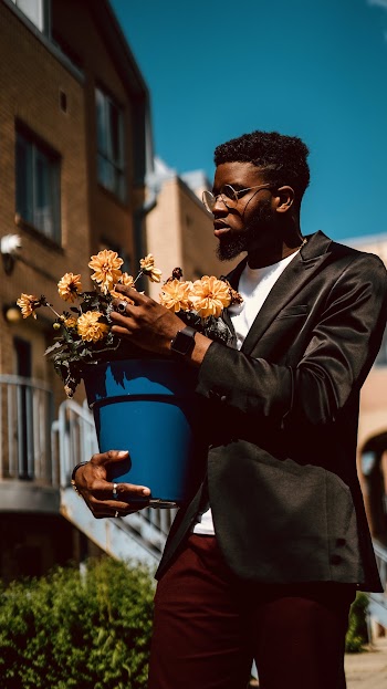 Photo of Man Carrying Pot of Flowers