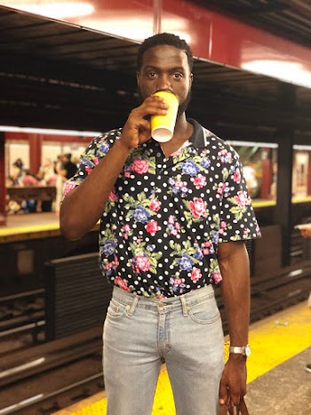 Photo of Man Drinking from Plastic Cup Posing While Standing on Subway Platform