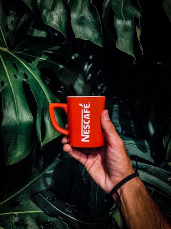 Photo of Man Holding a Red Nescafe Mug