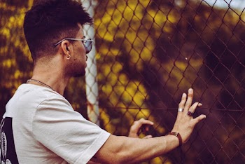 Photo of Man Holding Onto Fence