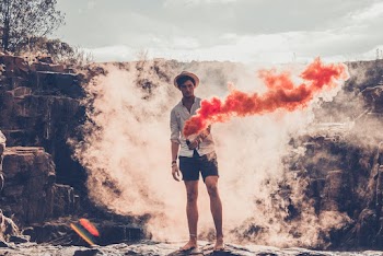 Photo of Man Holding Orange Smoke