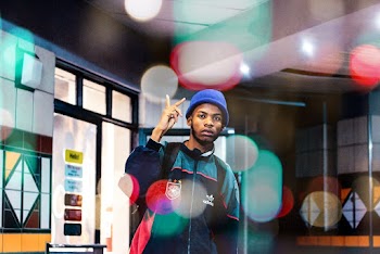 Photo of Man in Beanie Hat and Multicolored Jacket Posing While Doing the Peace Sign