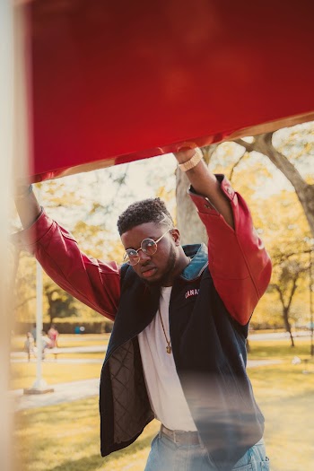 Photo of Man in Black and Red Jacket Holding Red Panel Posing