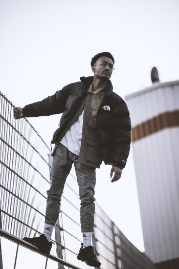 Photo of Man in Black Jacket Hanging on a Fence
