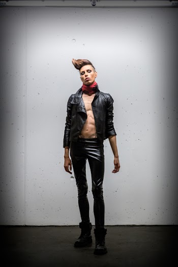Photo of Man in Black Jacket Standing in Front of Gray Wall