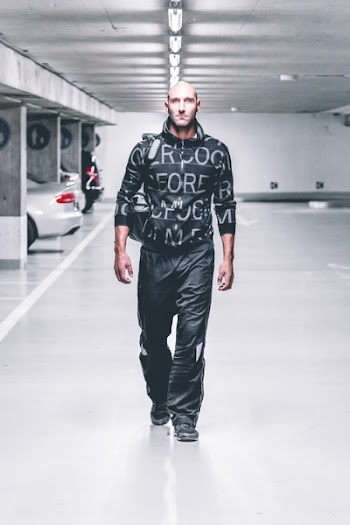 Photo of Man in Black Pants and Top Walking in Parking Lot