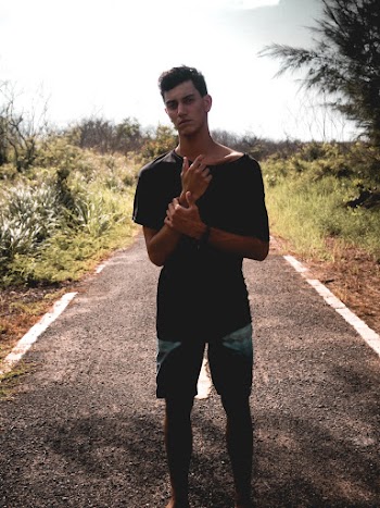 Photo of Man in Black T-shirt and Shorts Standing Alone in Middle of Pathway Posing