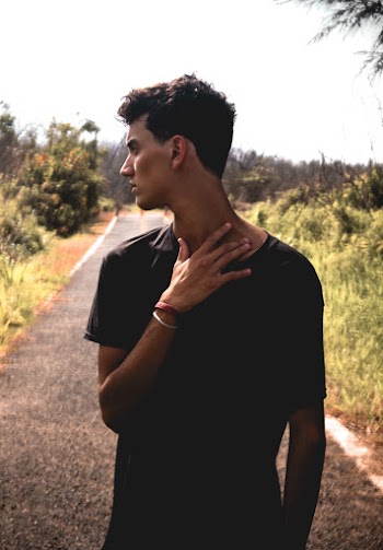 Photo of Man in Black T-shirt Standing Alone on Pathway Looking Away