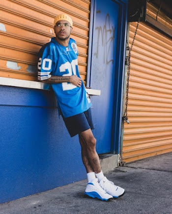 Photo of Man in Blue American Football Jersey and Blue Shorts Leaning on Closed Store Looking Away