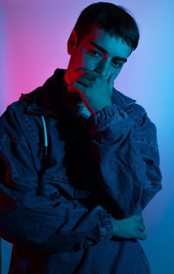 Photo of Man in Blue Denim Jacket Posing with Hand Over Mouth