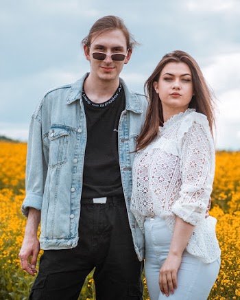 Photo of Man in Blue Denim Jacket Standing Beside Woman in White Mesh Blouse