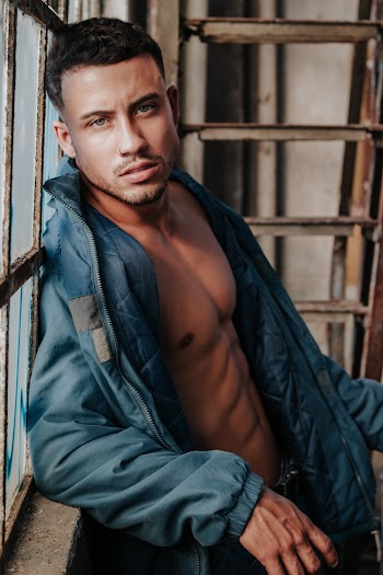 Photo of Man in Blue Zip-up Jacket Posing By Window Blue Zip-up Jacket