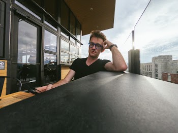 Photo of Man in Eyeglasses Sitting Beside Table