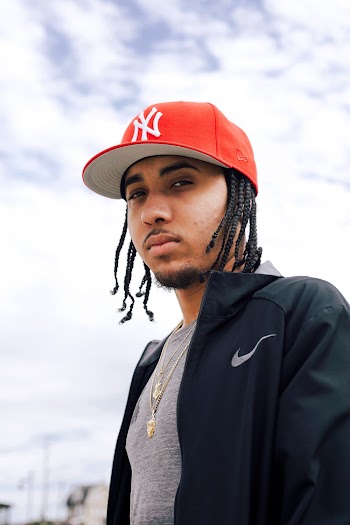 Photo of Man in Gray Shirt, Black Nike Jacket, and Red New York Yankees Cap Posing