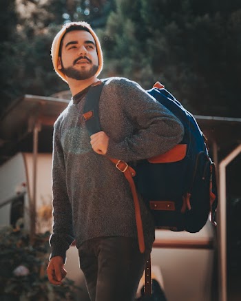 Photo of Man in Gray Swearer Standing Outside Carrying Blue and Brown Backpack