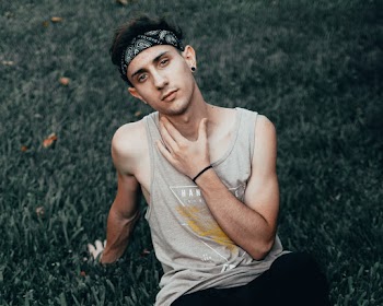 Photo of Man in Grey Tank Top Sitting on Grass