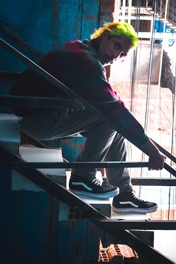 Photo of Man in Luminous Green Hair Sitting on Stairs Posing