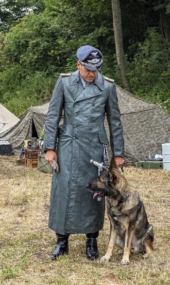 Photo of Man in Old Military Uniform Standing Next to German Shepherd