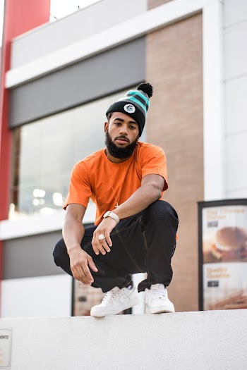 Photo of Man in Orange T-shirt and Black Denim Jeans Squat Posing