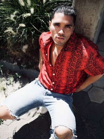 Photo of Man in Red Shirt Leaning on Stone Pillar While Squat Posing