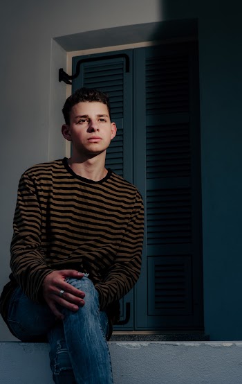 Photo of Man in Striped Long Sleeve Shirt Sitting with His Legs Crossed