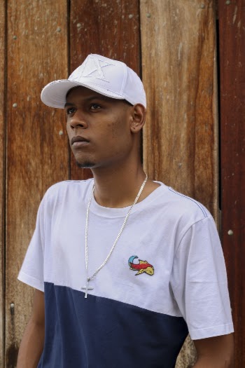 Photo of Man in White and Blue T-shirt and White Fitted Cap Standing Next to Wooden Wall
