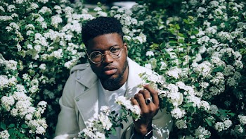 Photo of Man in White Jacket and T-shirt Posing by White Flowers