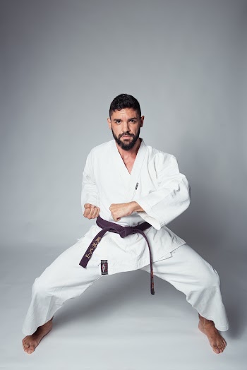 Photo of Man in White Karate Uniform Posing in Fighting Stance on a White Background
