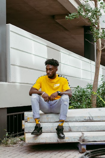 Photo of Man in Yellow T-shirt Sitting Beside Tree