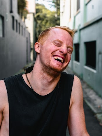 Photo of Man Laughing Between Buildings