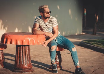 Photo of Man Leaning on Orange Concrete Table