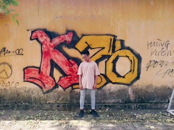 Photo of Man Looking Down Standing Beside Graffiti Wall