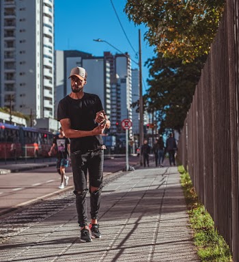 Photo of Man Posing on Sidewalk Next to Street