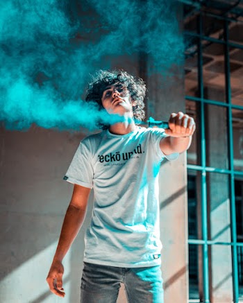 Photo of Man Posing While Holding Blue Smoke Bomb