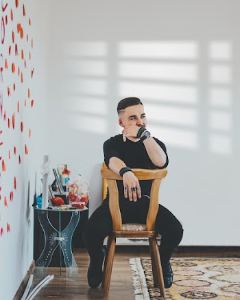 Photo of Man Sitting Backwards on Wooden Chair in Room Looking Away