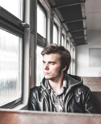 Photo of Man Sitting in Train Looking Outside Window