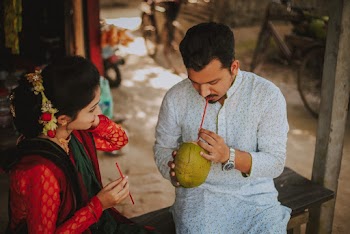 Photo of  Man Sitting on Bench Next To a Woman Sipping Coconut Water
