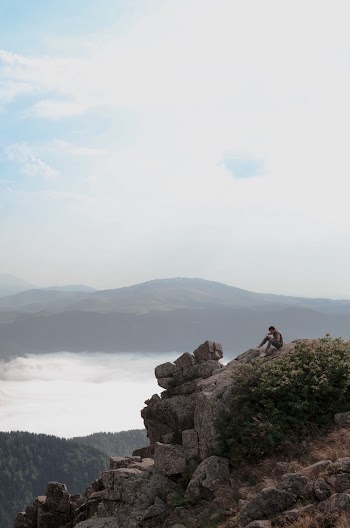 Photo of Man Sitting on Cliff