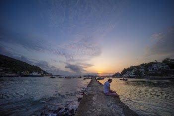 Photo of Man Sitting on Paved Pathway During Golden Hour