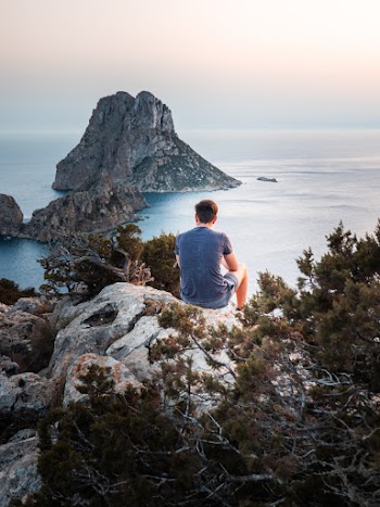 Photo Of Man Sitting On Top Of The Rock