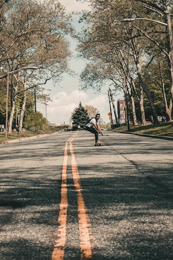 Photo of Man Skateboarding Down the Middle of the Road