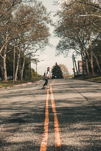 Photo of Man Skateboarding Down the Middle of the Road