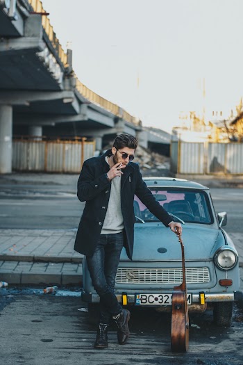 Photo of Man Smoking While Standing in Front of Old Car